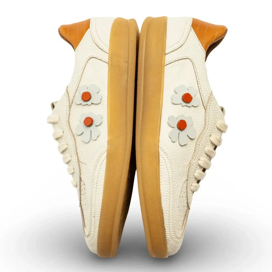 Pair of white sneakers with brown soles and flower 